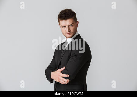 Portrait of a confident young businessman in suit looking away isolated over gray background Stock Photo