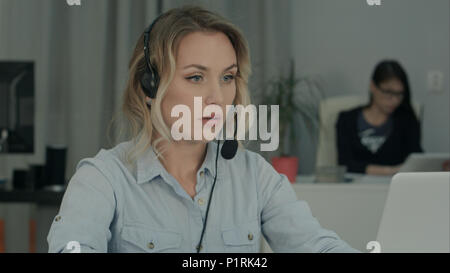 Call operator filling in client data on her laptop in the office Stock Photo