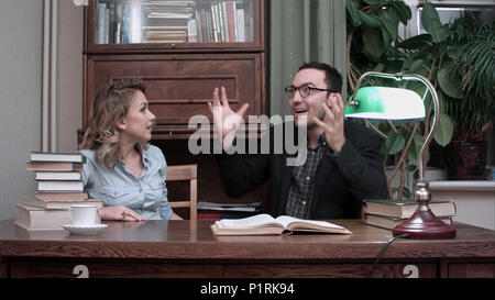Two young scientists having brainstorm sitting at the table with an opened book Stock Photo