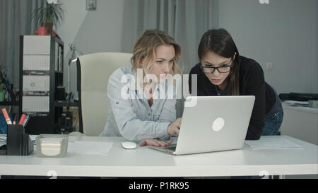 Two cheerful smiling young business women working on laptop Stock Photo