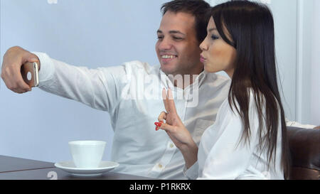 Young couple taking funny selfies on the phone in a cafe Stock Photo