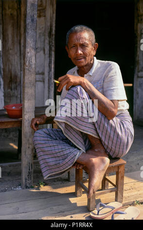 Portrait of a man with tattoos smoking on a porch; Mandalay; Myanmar Stock Photo