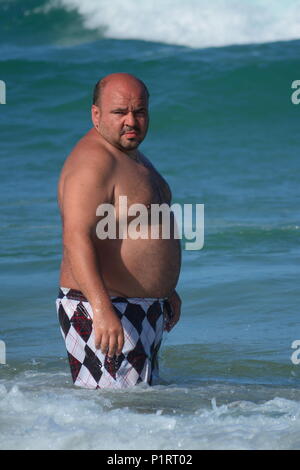 An overweight, obese man standing in the sea by beach Stock Photo