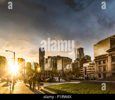A street scene in Vancouver at sunset with pedestrians and buildings reflecting sunlight; Vancouver, British Columbia, Canada Stock Photo
