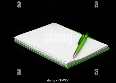 Blank green notepad with ballpoint pen isolated on black background Stock Photo