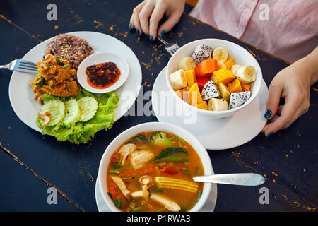 Thai traditional sour soup Tom Yam in vegetarian variation, curry rice and fruit salad in vegan restaurant in Bangkok Stock Photo