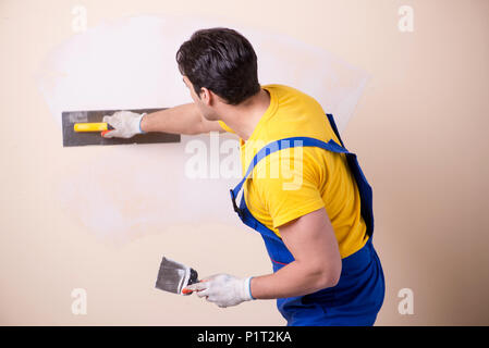 Young contractor employee applying plaster on wall Stock Photo
