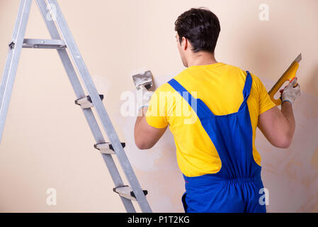Young contractor employee applying plaster on wall Stock Photo
