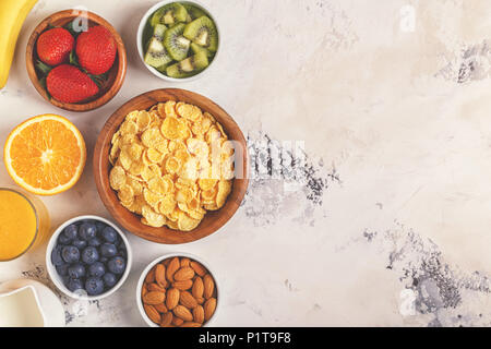 Healthy breakfast - bowl of corn flakes, berries and fruit, nuts, orange juice, milk, top view. Stock Photo