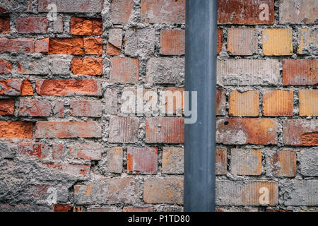 Grey plastic tube on a rugged brick wall. Background texture concept. Stock Photo