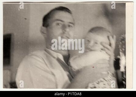 THE CZECHOSLOVAK SOCIALIST REPUBLIC - CIRCA 1950s: Retro photo shows father and toddler. Vintage black & white photography. With original film grain, blur and scratches. Stock Photo