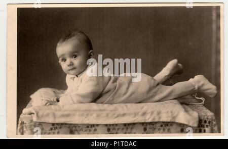 BEROUN, THE CZECHOSLOVAK REPUBLIC - MARCH 1, 1944: Retro photo shows toddler, lie prone. Vintage black & white photography. Stock Photo