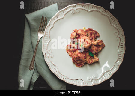 Tortellini with Tomato Sauce, Mozzarella Cheese and Basil on Big White Rustic Plate Stock Photo