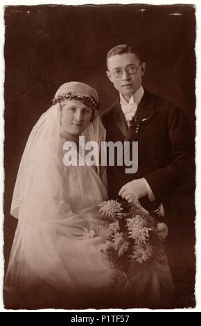 PRAHA (PRAGUE), THE CZECHOSLOVAK REPUBLIC - CIRCA 1930s: Vintage photo shows newlyweds. Groom wears glasses and bride wears long veil. Retro black & white wedding photography. Stock Photo