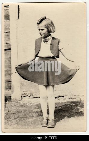 THE CZECHOSLOVAK REPUBLIC - CIRCA 1940s: Vintage photo shows a young girl outdoors. She shows her skirt proudly. Retro black & white photography. Stock Photo