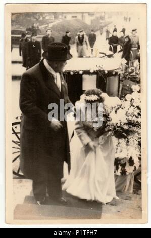 THE CZECHOSLOVAK REPUBLIC - CIRCA 1940s: Vintage photo shows a groom (bridegroom) and bride. A historical carriage (coach) is on the background. Retro black & white photography.past Stock Photo