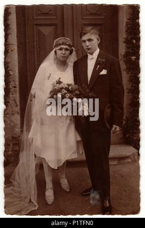 PRAHA (PRAGUE), THE CZECHOSLOVAK REPUBLIC - CIRCA 1930s: Vintage photo shows newlyweds go from wedding ceremony. Retro black & white photography. Stock Photo