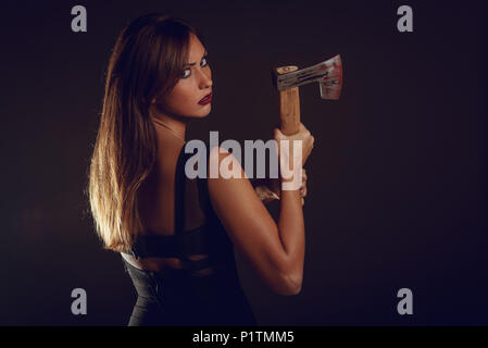 Beautiful dangerous girl with rusty axe want to revenge for violence she experience. Looking at camera. Stock Photo