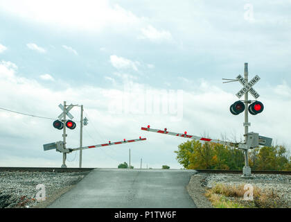 railroad crossing signal.  Arms are coming down and the lights are flashing. Stock Photo