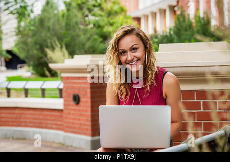 Portrait of a beautiful young female university student using her laptop outside on the campus; Edmonton, Alberta, Canada Stock Photo