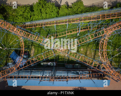 Aerial photography of a children's orange roller coaster with loops and rises in the hill in the city park   on a warm summer day. Helicopter drone sh Stock Photo