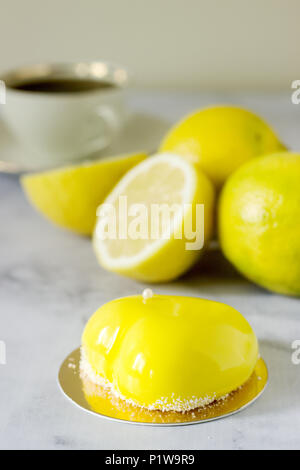 Mini glazed mousse lemon cake decorated with beads and coconut chips. Selective focus. Stock Photo