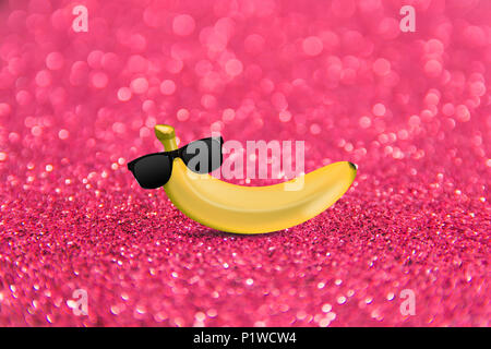 Colorful fruit pattern of fresh yellow bananas with glasses on pink background. From top view Stock Photo