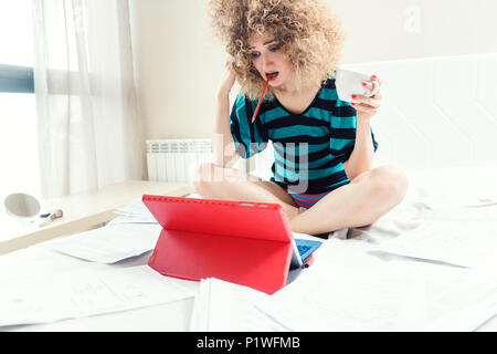 Telecommuting woman being desperate having no clue working on her bed Stock Photo