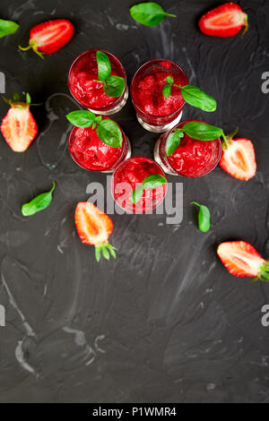 Summer refreshing strawberry sorbet, slush granita drink in serving glasses. Healthy low calorie summer treat, dessert. Iced Cocktail on black backgro Stock Photo