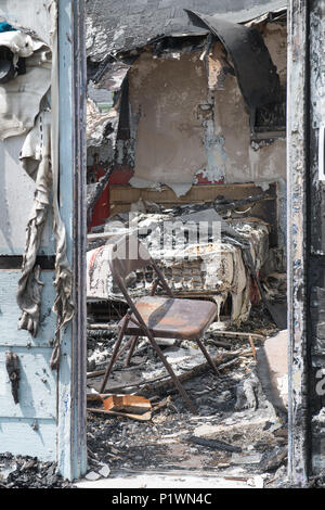 View through the door into a burned out bedroom with a mattress and folding chair