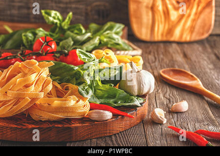 Products for cooking - pasta, tomatoes, garlic, pepper, and basil on the old wooden background. Stock Photo