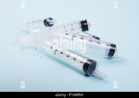 a stack of clear medical plastic syringes piled on top of each other neat and clean on a light blue background used for both human and animal purpose Stock Photo