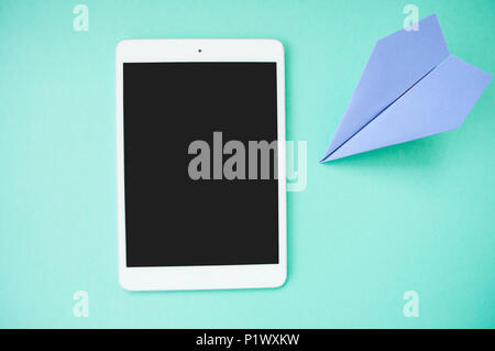 Flat lay of pink color desk with tablet and pastel violet paper plane with text space.