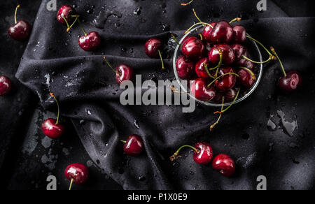 Sweet ripe cherries on dark tablecloth with water drops. Stock Photo