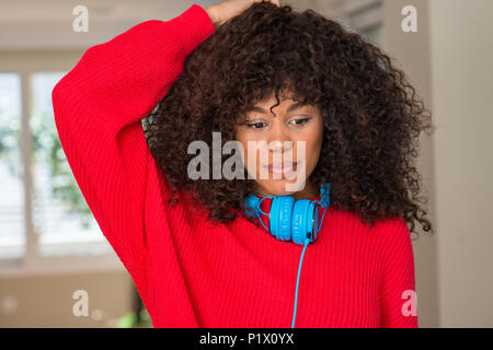 African american woman wearing headphones confuse and wonder about question. Uncertain with doubt, thinking with hand on head. Pensive concept. Stock Photo