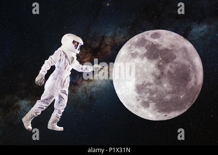 Astronaut in space and moon exploration. Concept, astronaut pulls his hand to the lunar surface. Elements of this image furnished by NASA. Stock Photo