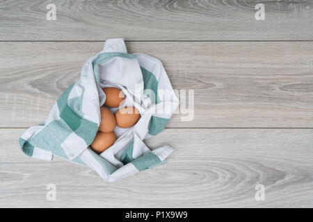 some eggs in a rag on the wooden table in the kitchen Stock Photo