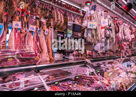 Spain, Barcelona - March 27, 2018: Boqueria market, jamon and sausages on the counter of the Spanish market Stock Photo