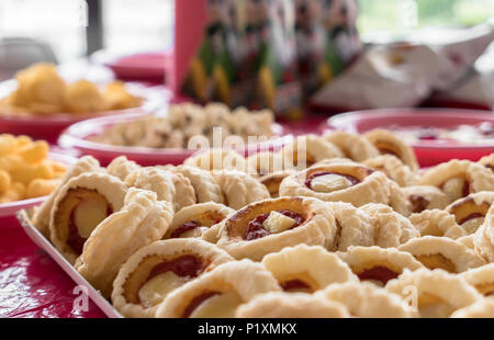 Close-up to mini pizzas and on blurry background, fries chips and popcorn. Food for parties, birthdays and holidays. Defocused blurry background. Stock Photo