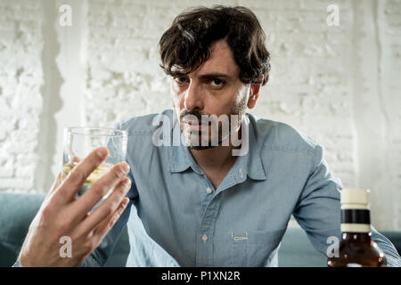 drunk alcoholic lain business man drinking whiskey from the bottle and glass depressed wasted and sad at home couch in alcohol abuse and alcoholism co Stock Photo