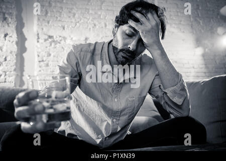 drunk alcoholic lain business man drinking whiskey from the bottle and glass depressed wasted and sad at home couch in alcohol abuse and alcoholism co Stock Photo