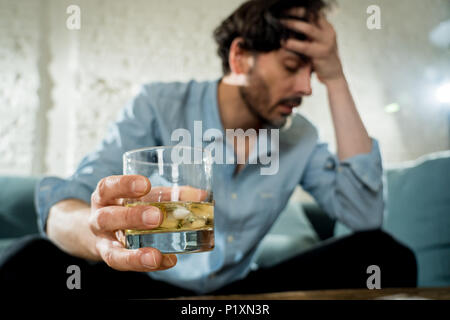 drunk alcoholic lain business man drinking whiskey from the bottle and glass depressed wasted and sad at home couch in alcohol abuse and alcoholism co Stock Photo