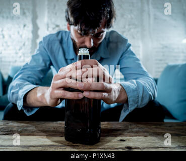 drunk alcoholic lain business man drinking whiskey from the bottle and glass depressed wasted and sad at home couch in alcohol abuse and alcoholism co Stock Photo