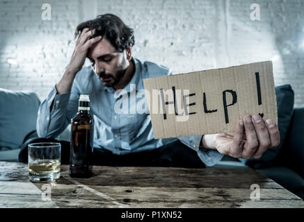 drunk alcoholic lain business man drinking whiskey from the bottle and glass depressed wasted and sad at home couch in alcohol abuse and alcoholism co Stock Photo