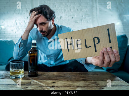 drunk alcoholic lain business man drinking whiskey from the bottle and glass depressed wasted and sad at home couch in alcohol abuse and alcoholism co Stock Photo