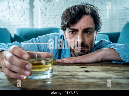 drunk alcoholic lain business man drinking whiskey from the bottle and glass depressed wasted and sad at home couch in alcohol abuse and alcoholism co Stock Photo