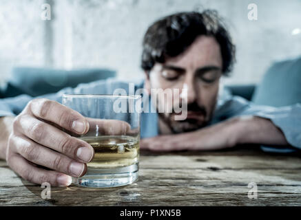 drunk alcoholic lain business man drinking whiskey from the bottle and glass depressed wasted and sad at home couch in alcohol abuse and alcoholism co Stock Photo