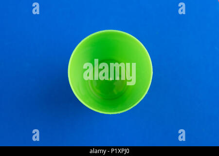 Green plastic cup shot from above on blue background Stock Photo