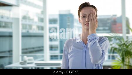 Businesswoman holding hand over one eye in office being tired Stock Photo
