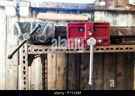Old vices attached to a homemade workbench in an abandoned shed Stock Photo